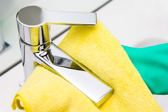 Photo of a very clean and shiny tap with yellow and green cloths in a wash basin